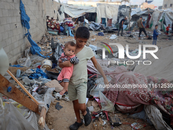 Children stand in the midst of the destruction in the aftermath of a reported overnight Israeli strike that hits tents used as temporary she...