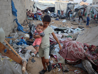 Children stand in the midst of the destruction in the aftermath of a reported overnight Israeli strike that hits tents used as temporary she...