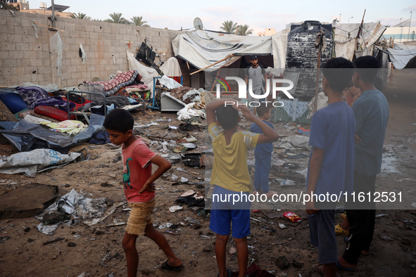 Children stand in the midst of the destruction in the aftermath of a reported overnight Israeli strike that hits tents used as temporary she...