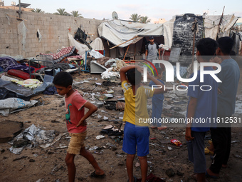 Children stand in the midst of the destruction in the aftermath of a reported overnight Israeli strike that hits tents used as temporary she...