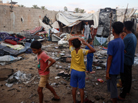 Children stand in the midst of the destruction in the aftermath of a reported overnight Israeli strike that hits tents used as temporary she...