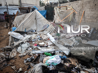 People stand amidst the destruction after a reported overnight Israeli strike that hits tents used as temporary shelters by displaced Palest...