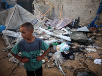 A young boy stands amidst the destruction after a reported overnight Israeli strike that hits tents used as temporary shelters by displaced...