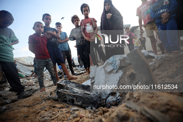 Children stand in the midst of the destruction in the aftermath of a reported overnight Israeli strike that hits tents used as temporary she...