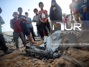 Children stand in the midst of the destruction in the aftermath of a reported overnight Israeli strike that hits tents used as temporary she...