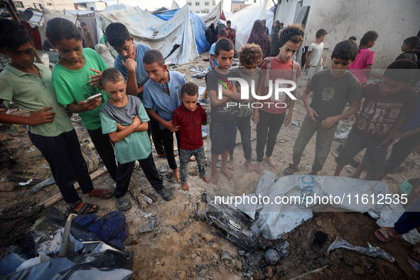 Children stand in the midst of the destruction in the aftermath of a reported overnight Israeli strike that hits tents used as temporary she...