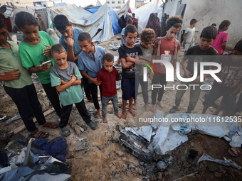 Children stand in the midst of the destruction in the aftermath of a reported overnight Israeli strike that hits tents used as temporary she...