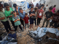 Children stand in the midst of the destruction in the aftermath of a reported overnight Israeli strike that hits tents used as temporary she...