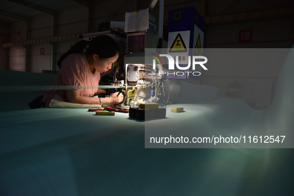 A worker works on a paper-making net production line at Pacific Special Mesh Co., LTD in Fuyang, China, on September 27, 2024. 