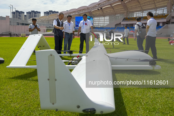 Aviation enthusiasts look at drones at the event site of the 2024 China International Aircraft Design Challenge (Fujian Station) at the new...