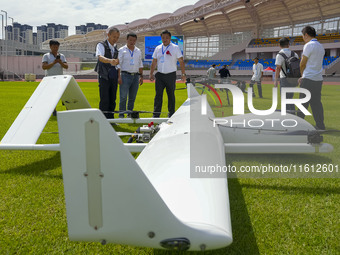 Aviation enthusiasts look at drones at the event site of the 2024 China International Aircraft Design Challenge (Fujian Station) at the new...