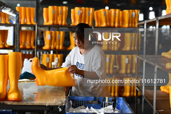 A worker works on a production line of rain rubber shoes at Guanhong Plastic Industry Co., LTD in Jieshou, China, on September 27, 2024. 