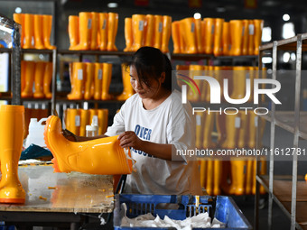 A worker works on a production line of rain rubber shoes at Guanhong Plastic Industry Co., LTD in Jieshou, China, on September 27, 2024. (