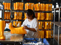 A worker works on a production line of rain rubber shoes at Guanhong Plastic Industry Co., LTD in Jieshou, China, on September 27, 2024. (