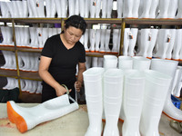 A worker works on a production line of rain rubber shoes at Guanhong Plastic Industry Co., LTD in Jieshou, China, on September 27, 2024. (