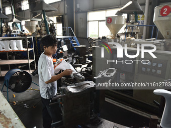 A worker works on a production line of rain rubber shoes at Guanhong Plastic Industry Co., LTD in Jieshou, China, on September 27, 2024. (