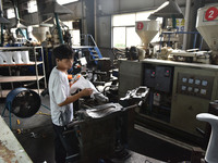 A worker works on a production line of rain rubber shoes at Guanhong Plastic Industry Co., LTD in Jieshou, China, on September 27, 2024. (