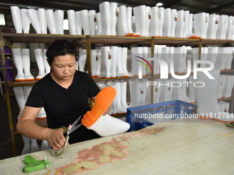 A worker works on a production line of rain rubber shoes at Guanhong Plastic Industry Co., LTD in Jieshou, China, on September 27, 2024. (