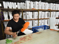 A worker works on a production line of rain rubber shoes at Guanhong Plastic Industry Co., LTD in Jieshou, China, on September 27, 2024. (