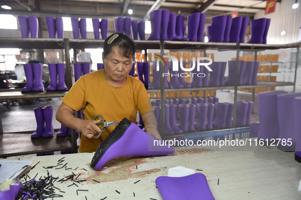 A worker works on a production line of rain rubber shoes at Guanhong Plastic Industry Co., LTD in Jieshou, China, on September 27, 2024. 