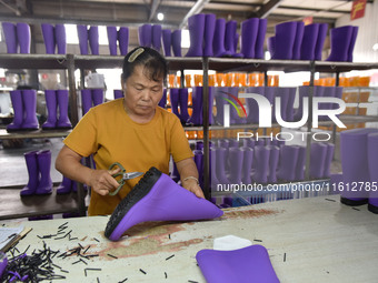 A worker works on a production line of rain rubber shoes at Guanhong Plastic Industry Co., LTD in Jieshou, China, on September 27, 2024. (