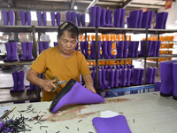 A worker works on a production line of rain rubber shoes at Guanhong Plastic Industry Co., LTD in Jieshou, China, on September 27, 2024. (