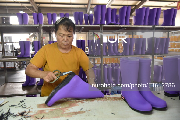 A worker works on a production line of rain rubber shoes at Guanhong Plastic Industry Co., LTD in Jieshou, China, on September 27, 2024. 