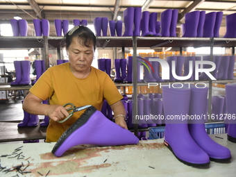 A worker works on a production line of rain rubber shoes at Guanhong Plastic Industry Co., LTD in Jieshou, China, on September 27, 2024. (