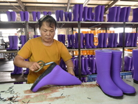 A worker works on a production line of rain rubber shoes at Guanhong Plastic Industry Co., LTD in Jieshou, China, on September 27, 2024. (