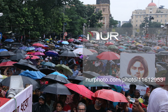 People protest amid heavy rain during a rally against the rape and murder of a PGT woman doctor at the government-run R G Kar Medical Colleg...