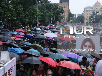 People protest amid heavy rain during a rally against the rape and murder of a PGT woman doctor at the government-run R G Kar Medical Colleg...