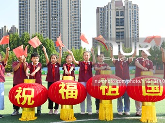 Students of Chuzhou No. 4 Primary School in Chuzhou, China, on September 27, 2024, carry red lanterns printed with the words ''Bless the mot...