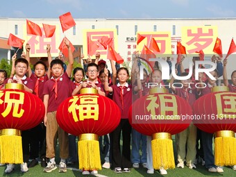 Students of Chuzhou No. 4 Primary School in Chuzhou, China, on September 27, 2024, carry red lanterns printed with the words ''Bless the mot...