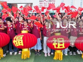 Students of Chuzhou No. 4 Primary School in Chuzhou, China, on September 27, 2024, carry red lanterns printed with the words ''Bless the mot...