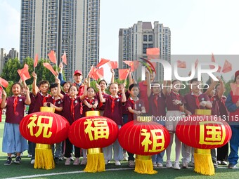 Students of Chuzhou No. 4 Primary School in Chuzhou, China, on September 27, 2024, carry red lanterns printed with the words ''Bless the mot...