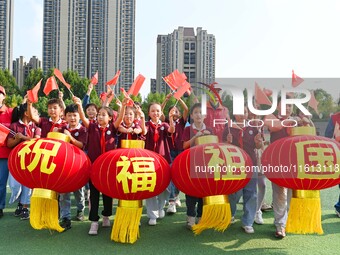 Students of Chuzhou No. 4 Primary School in Chuzhou, China, on September 27, 2024, carry red lanterns printed with the words ''Bless the mot...