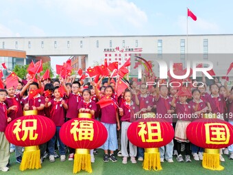 Students of Chuzhou No. 4 Primary School in Chuzhou, China, on September 27, 2024, carry red lanterns printed with the words ''Bless the mot...