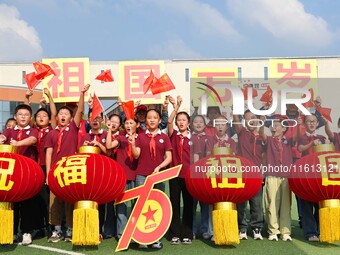 Students of Chuzhou No. 4 Primary School in Chuzhou, China, on September 27, 2024, carry red lanterns printed with the words ''Bless the mot...