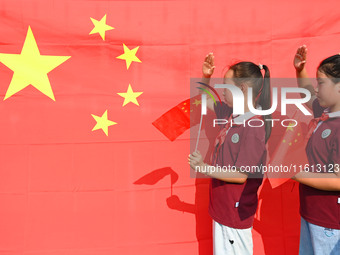 Students of Chuzhou No. 4 Primary School in Chuzhou, China, on September 27, 2024, take a photo with the national flag to welcome National D...