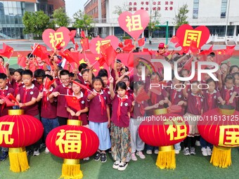 Students of Chuzhou No. 4 Primary School in Chuzhou, China, on September 27, 2024, carry red lanterns printed with the words ''Bless the mot...