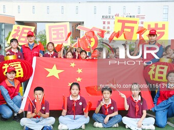 Students of Chuzhou No. 4 Primary School in Chuzhou, China, on September 27, 2024, take a photo with the national flag to welcome National D...