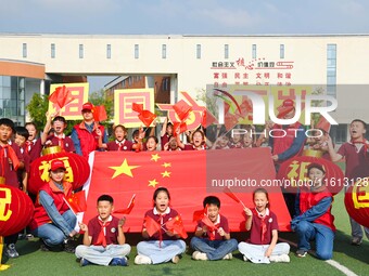 Students of Chuzhou No. 4 Primary School in Chuzhou, China, on September 27, 2024, carry red lanterns printed with the words ''Bless the mot...