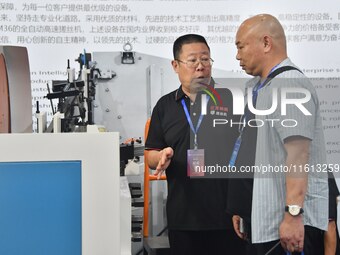 An exhibitor introduces production equipment to a buyer at the 17th China Handan (Yongnian) Fastener and Equipment Exhibition in Handan, Chi...