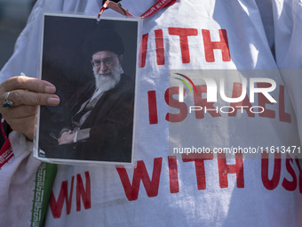 An Iranian female protester, wearing a shroud covered with anti-U.S. and anti-Israeli slogans, holds a portrait of Iran's Supreme Leader Aya...