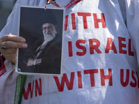 An Iranian female protester, wearing a shroud covered with anti-U.S. and anti-Israeli slogans, holds a portrait of Iran's Supreme Leader Aya...