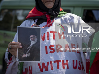 An Iranian female protester, wearing a shroud covered with anti-U.S. and anti-Israeli slogans, holds a portrait of Iran's Supreme Leader Aya...