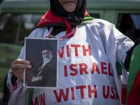 An Iranian female protester, wearing a shroud covered with anti-U.S. and anti-Israeli slogans, holds a portrait of Iran's Supreme Leader Aya...