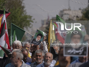 An Iranian worshipper carries a portrait of Lebanon's Hezbollah Secretary General, Hassan Nasrallah, during an anti-Israeli protest to conde...