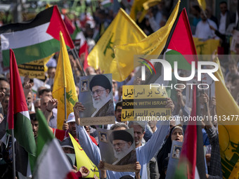 Iranian worshippers carry an anti-Israeli placard and portraits of Iran's Supreme Leader, Ayatollah Ali Khamenei, during an anti-Israeli pro...