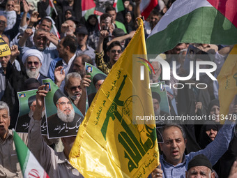 Iranian worshippers carry portraits of Lebanon's Hezbollah Secretary General, Hassan Nasrallah, during an anti-Israeli protest to condemn Is...